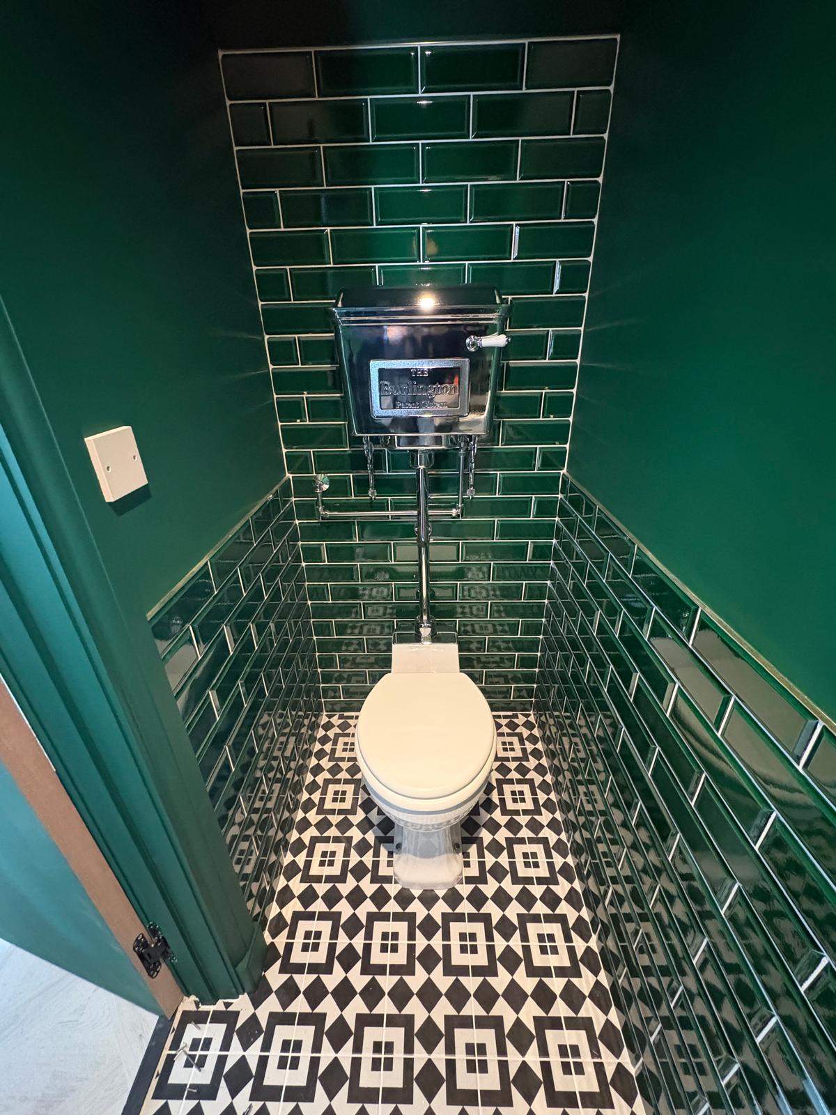 Statement downstairs cloakroom with bevelled emerald metro tiling, traditional Burlington high-level cistern, chrome pipework and Victorian-style patterned floor tiles.