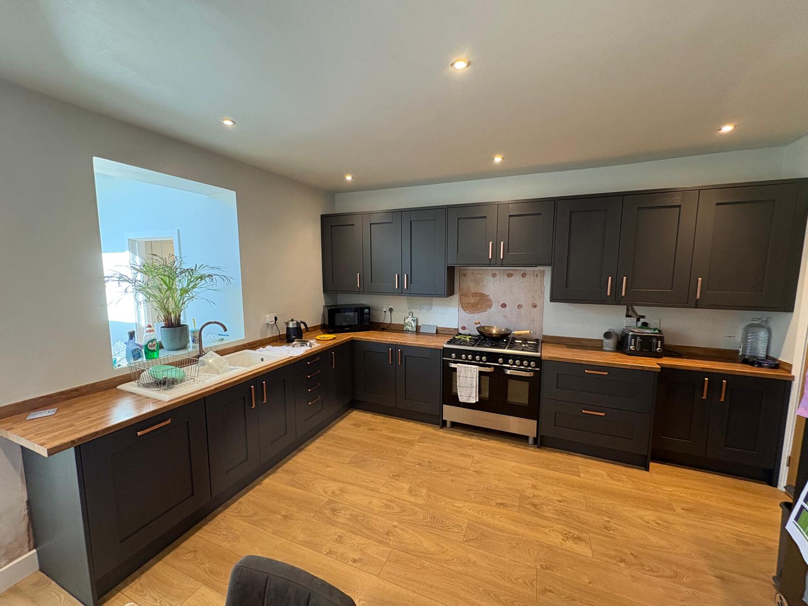 Full kitchen refit with charcoal shaker units, solid oak worktops, copper handles, range cooker and integrated serving hatch.