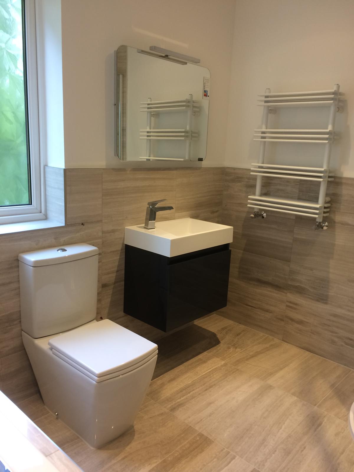Downstairs cloakroom finished in wood-effect porcelain with wall-hung gloss vanity, square basin and designer ladder radiator.