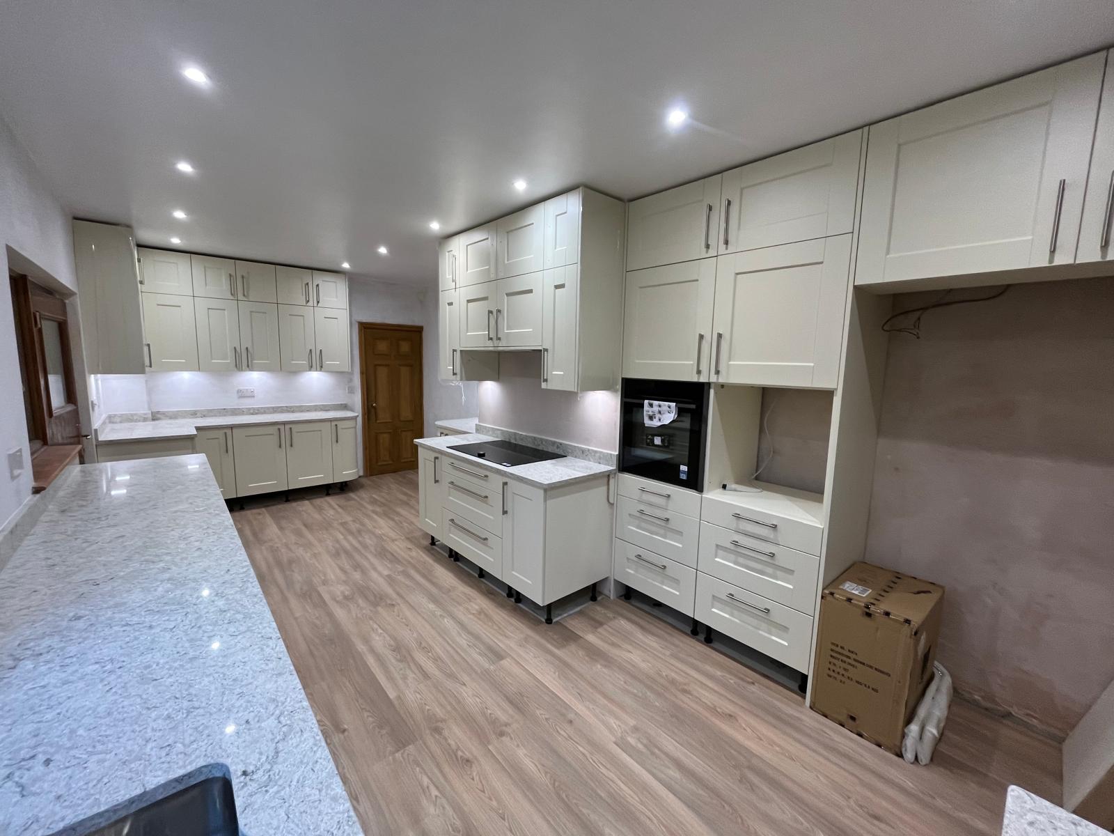Full kitchen refit with cream shaker units, marble-effect worktops, integrated oven and induction hob, finished with engineered oak flooring.