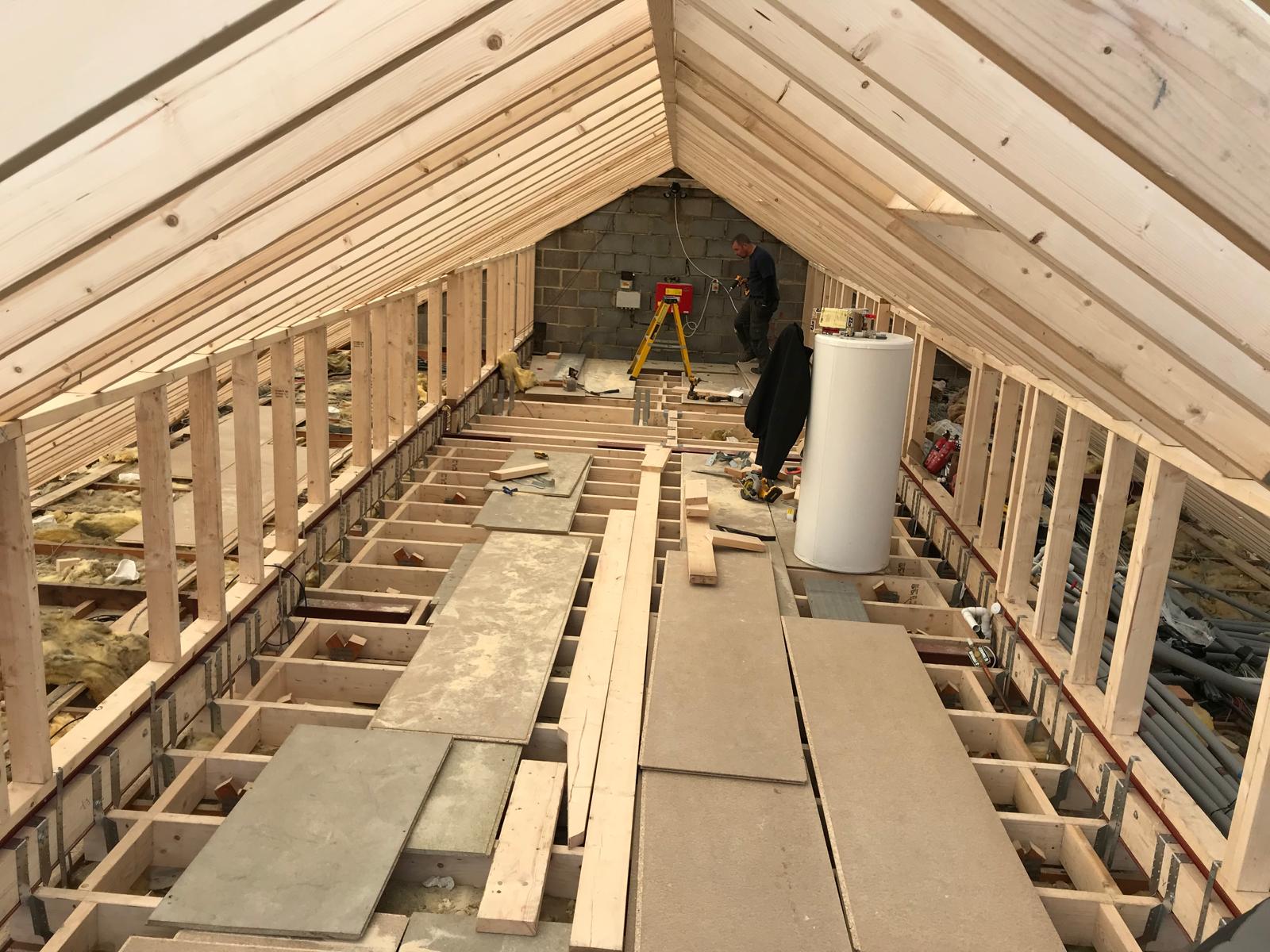 Internal timber framing, joist deck and first-fix electrics installed within the newly trussed roof space, ready for insulation and plasterboard.