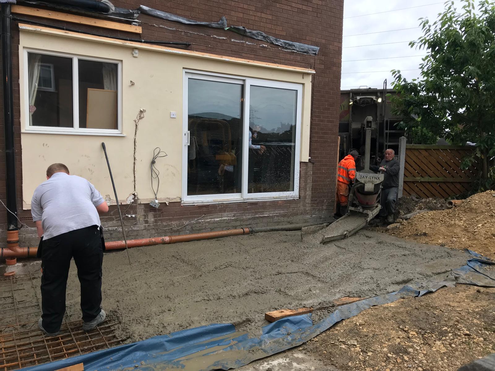 Bay-Lynx concrete wagon pouring a reinforced ground slab for a new rear extension, with mesh reinforcement, DPM and edge formwork all set ready.