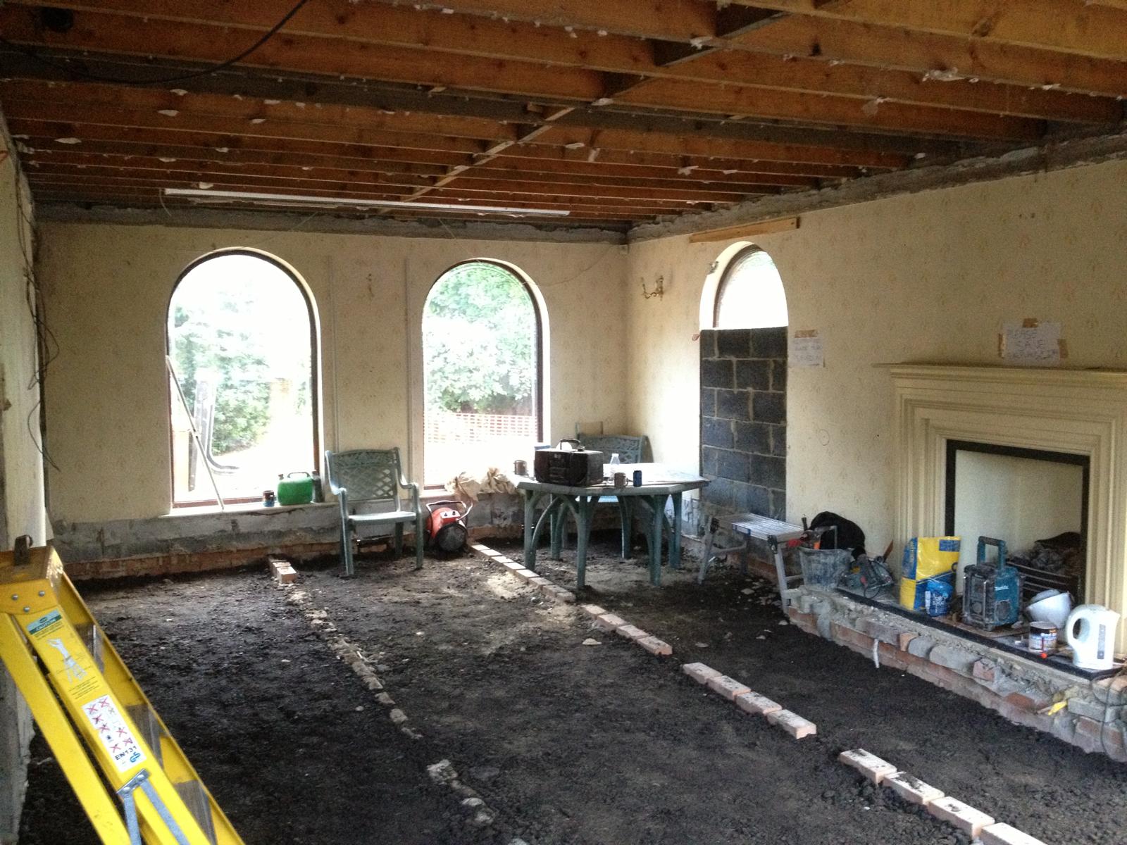 Living space taken back to bare walls and joists, original arched windows and stone fireplace protected ready for full refurbishment.