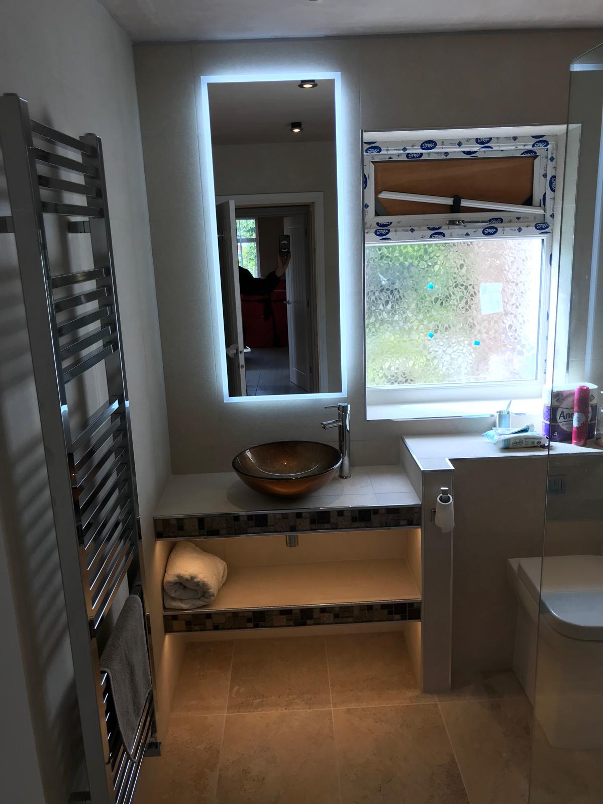 Bespoke en-suite with floating vanity, copper glass vessel basin, LED mirror and twin-tier shelving with under-lighting.